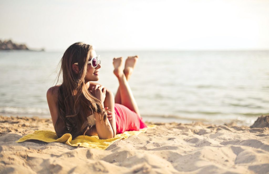 Une femme se detend sur sa serviette de plage, signaux de bien-etre