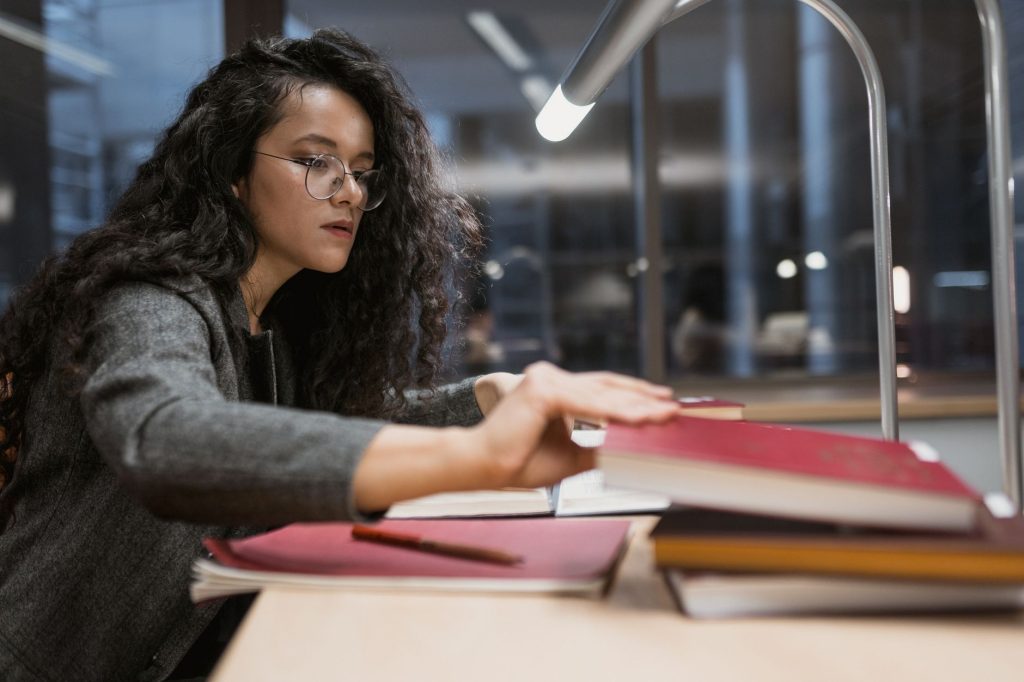 Étudiante concentrée en train de réviser et de mémoriser ses notes dans une bibliothèque
