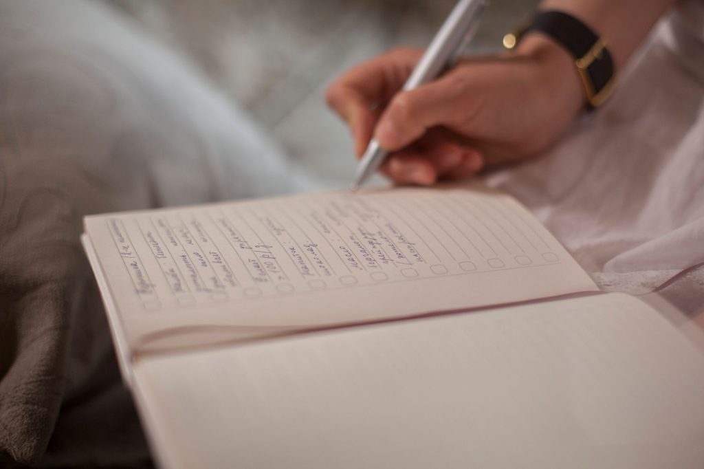 Liste de tâches et carnet manuscrit posant sur un bureau, illustrant le besoin de tout planifier