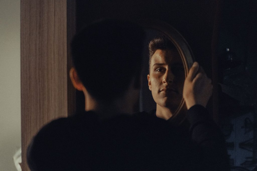 Personne face à son reflet dans un miroir, symbole de l'introspection et de la lucidité sur ses propres contradictions