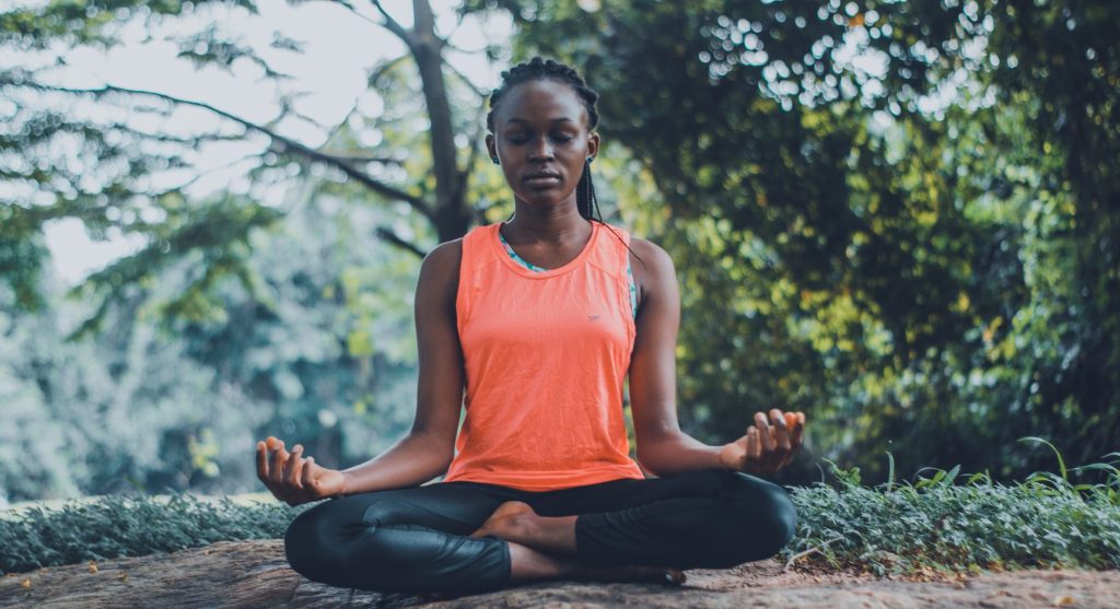 Femme méditant en extérieur dans un environnement naturel et apaisé