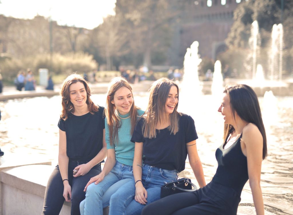 Groupe d'amis souriants partageant une conversation animée en extérieur