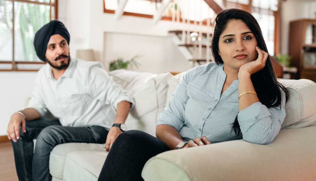 Couple assis à distance sur un canapé, communication émotionnelle difficile