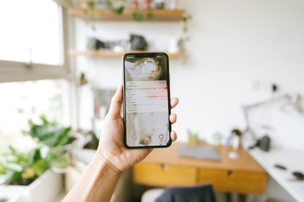 Main tenant un smartphone affichant des notifications, principale source d’interruption de l’attention