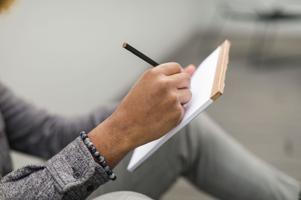 Personne écrivant dans un carnet, exercice du journal des émotions
