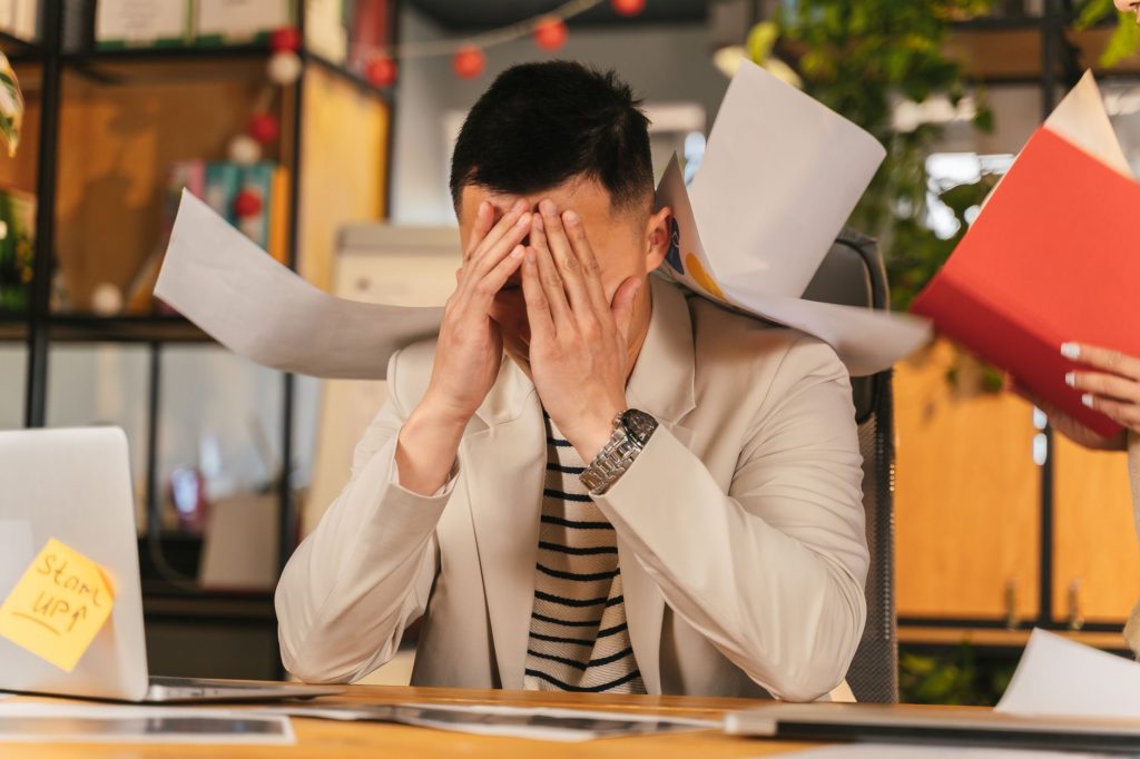 Personne stressée devant son ordinateur au bureau, submergée par la charge de travail