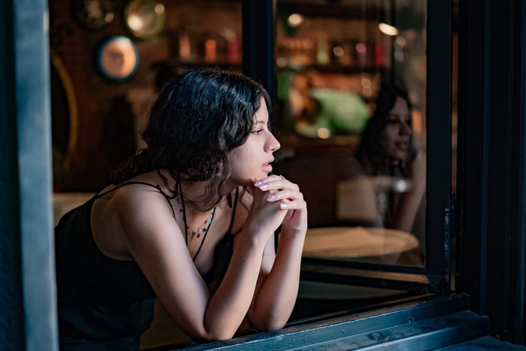 Femme pensive regardant par la fenêtre après avoir découvert une infidélité