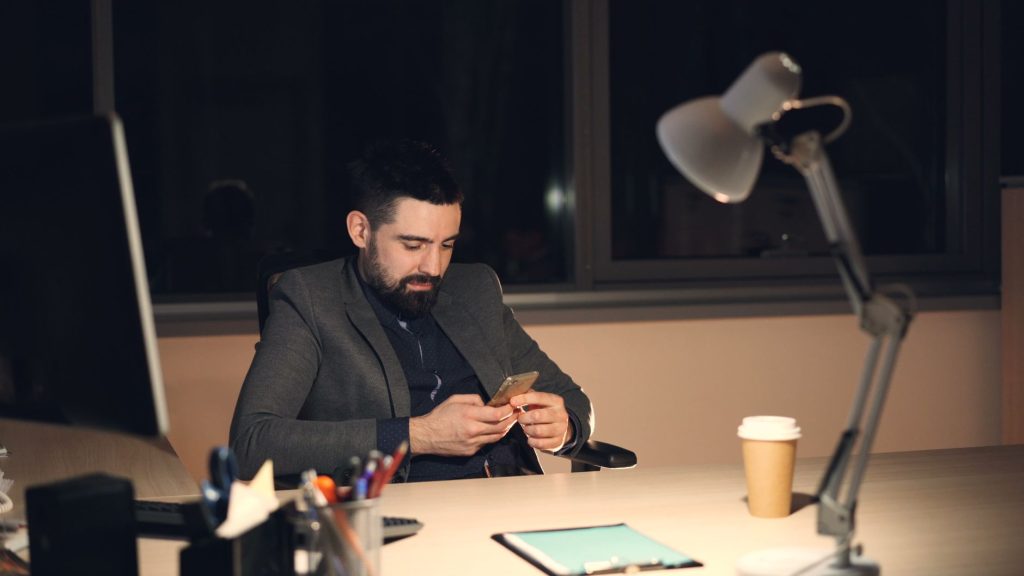 Homme consultant discrètement son téléphone le soir, illustration d’une double vie