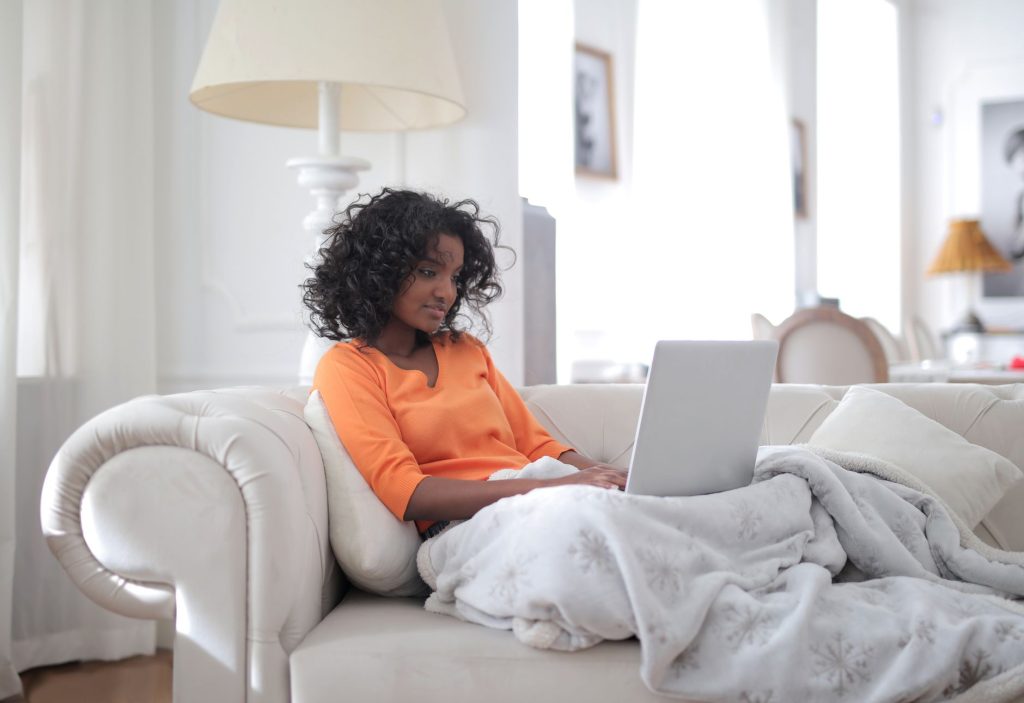 Jeune femme écrivant sur un ordinateur portable, absorbée dans ses pensées