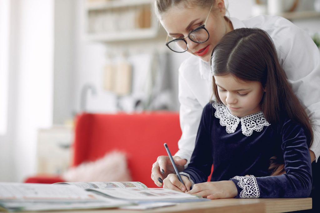 Un adulte accompagne un enfant pendant un exercice d’écriture