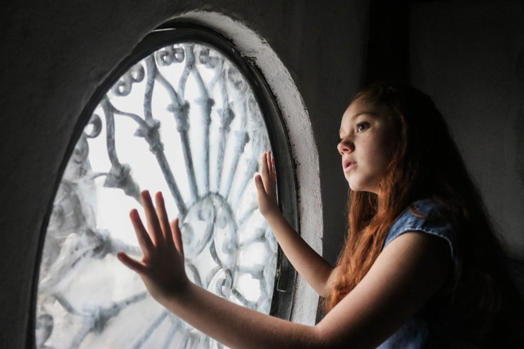 Adolescente pensive regardant par la fenêtre de sa chambre