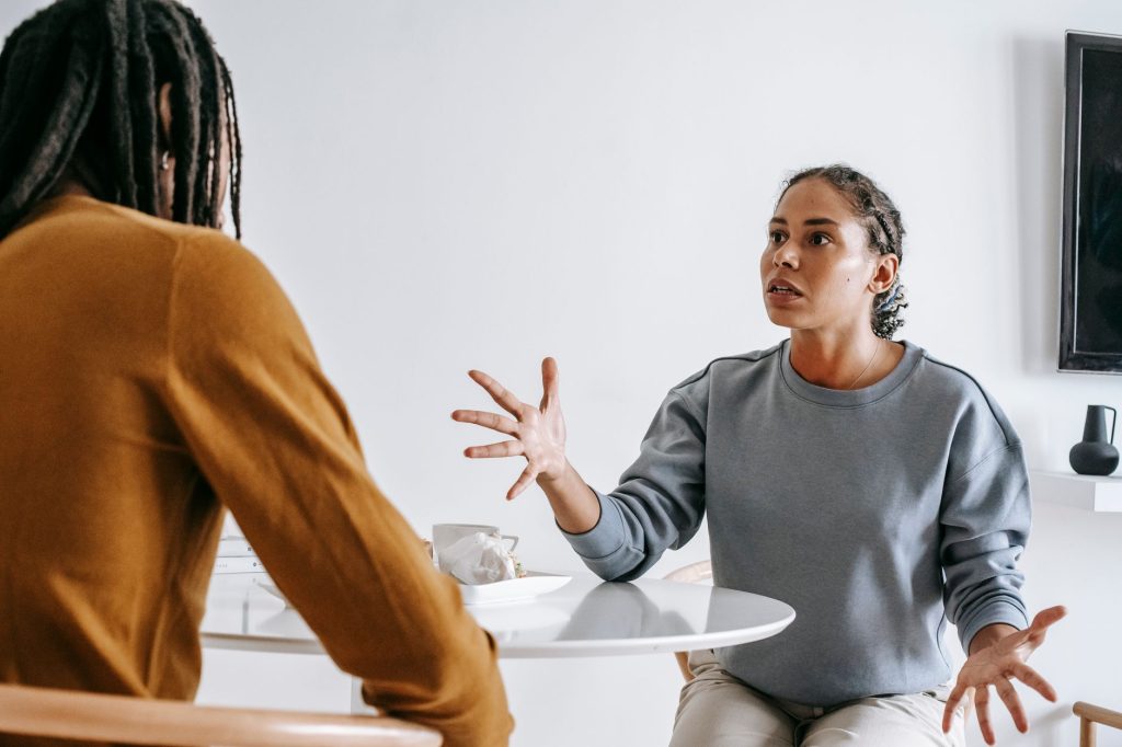 Couple assis face à face autour d’une table pour une conversation sincère sur l’avenir de leur relation