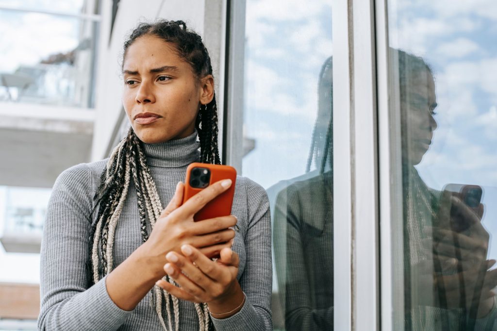 Femme pensive tenant son téléphone, hésitant à envoyer un message à son ex