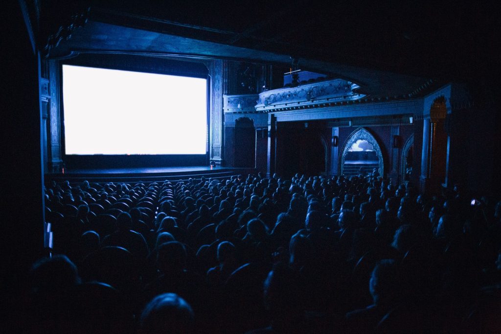 Salle de cinéma plongée dans le noir face à un écran, lieu du mythe fondateur des images subliminales