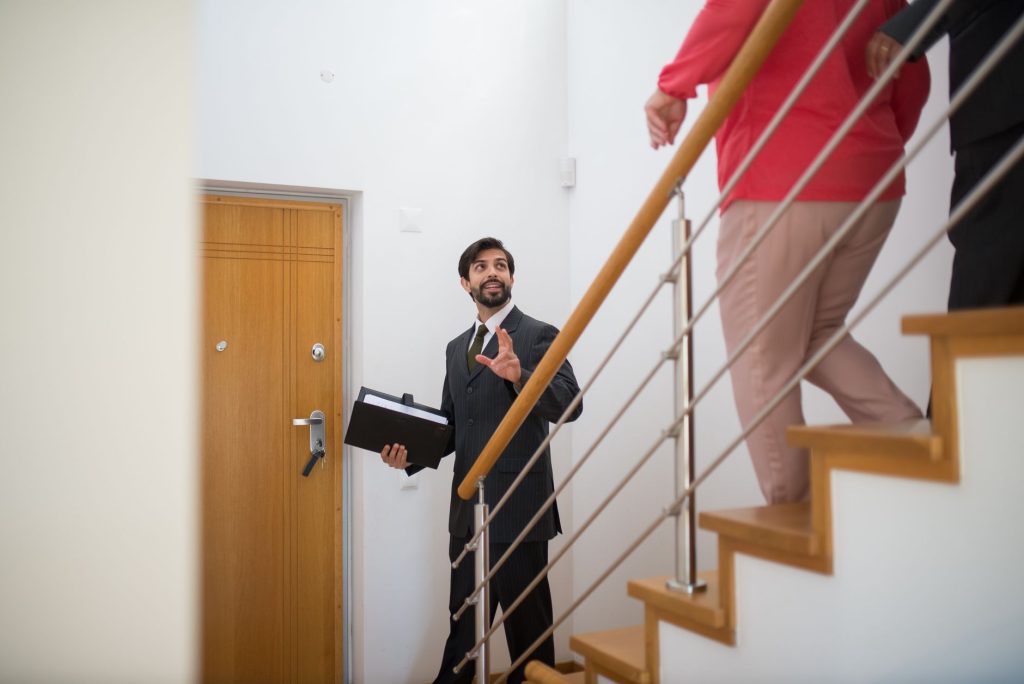 Négociateur immobilier accueillant des clients lors d'une visite, métier en N accessible sans diplôme supérieur