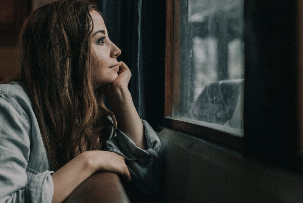 Femme pensive regardant par la fenêtre pendant une pause dans son couple