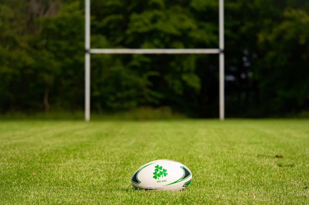 Supporters debout dans les tribunes, écharpes levées, pendant une rencontre de rugby