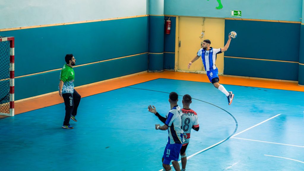 Deux équipes de handball en plein match, ballon en jeu