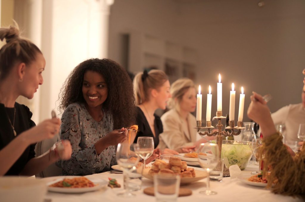 Groupe d’amis attablés qui rient ensemble lors d’un dîner, illustrant les rencontres par le cercle amical