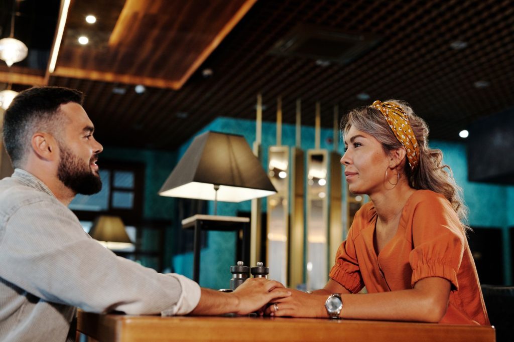 Deux personnes assises face à face dans un café, en pleine conversation détendue