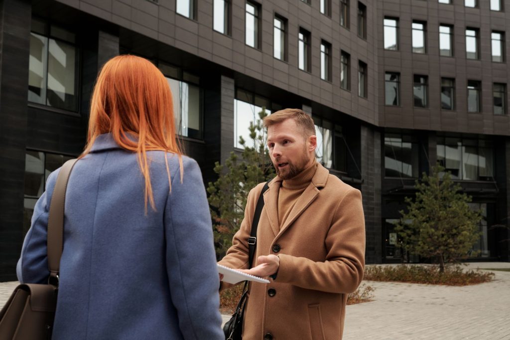 Un homme et une femme discutent en extérieur, dans une posture complice mais réservée