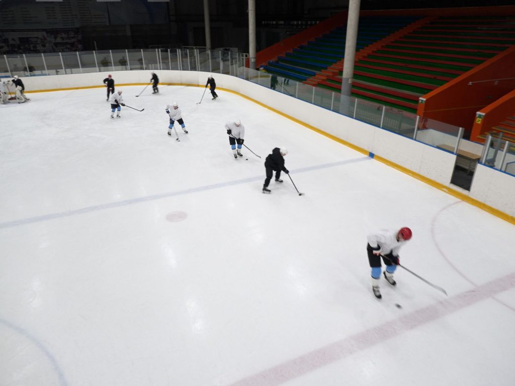 Patineurs pratiquant un sport de glace en intérieur sur une patinoire
