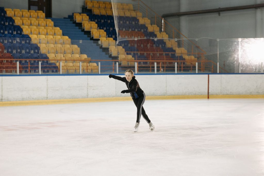 Patineuse artistique en pleine figure sur la glace, illustrant l'équilibre et la souplesse requis dans ce sport en P