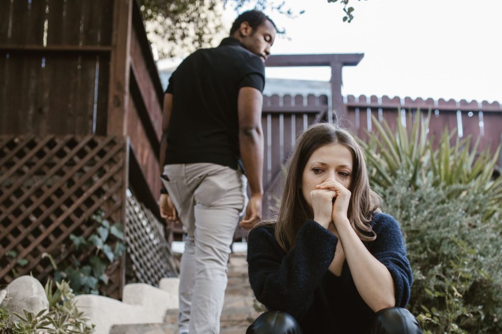 Femme pensive près d’une fenêtre, illustrant un blocage amoureux malgré des sentiments sincères