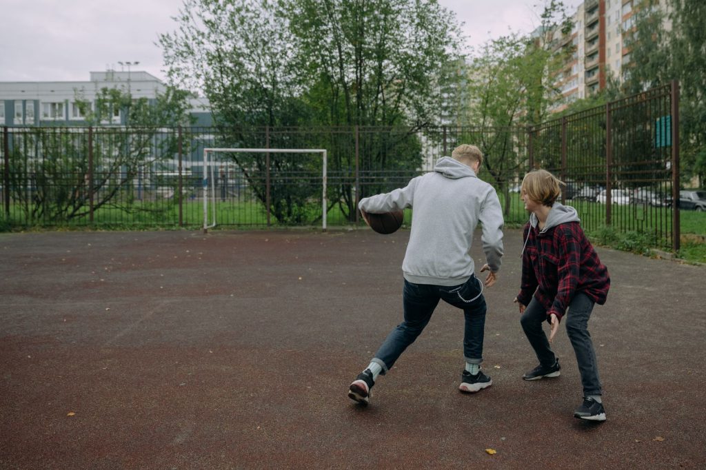 Amis jouant au streetball sur un terrain extérieur