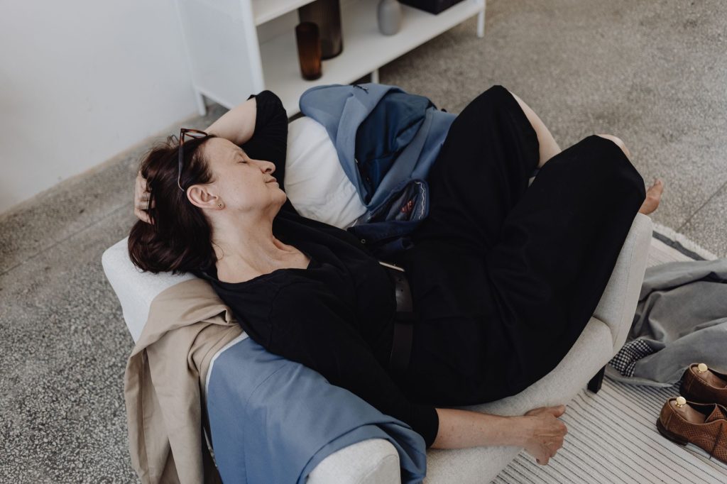 Une femme épuisée allongée sur son canapé en fin de journée, illustrant la fatigue comme frein au désir