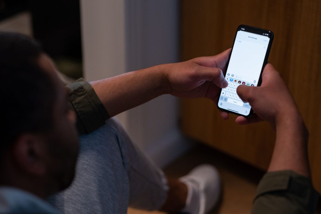 Un homme écrit un message sur son smartphone en fin de journée